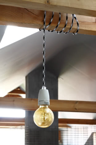 Designerska lampa-żarówka z kolorowym kablem na poddaszu