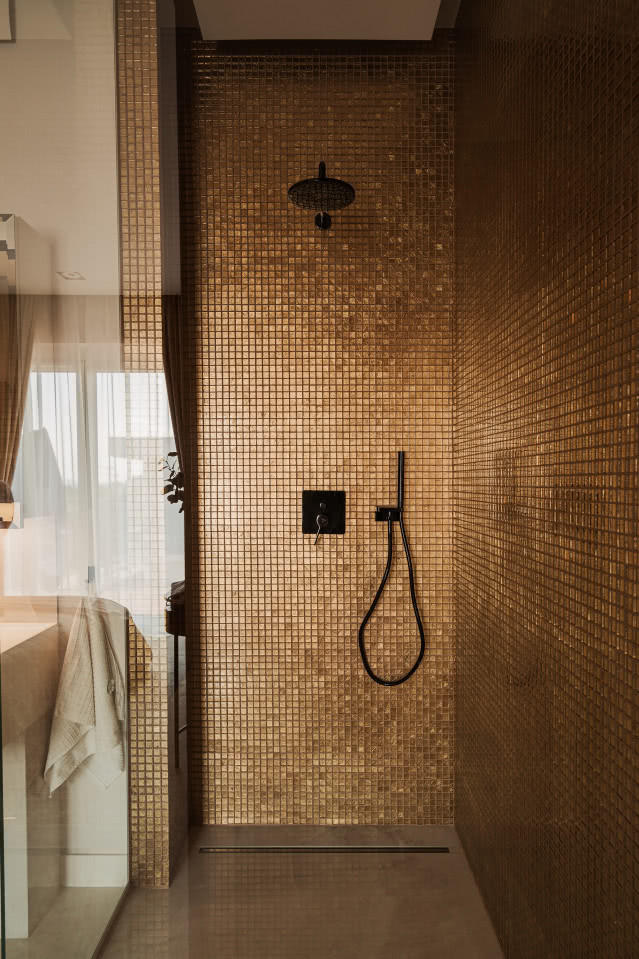 Złote płytki pod prysznicem w łazience