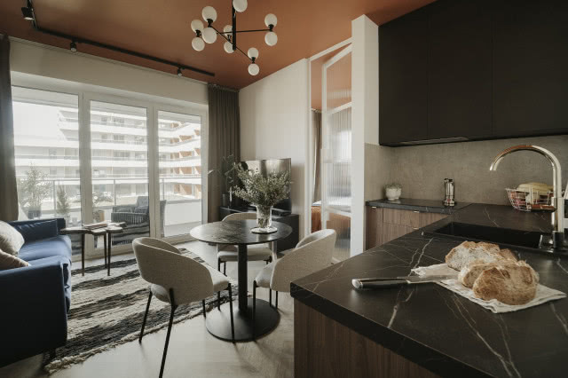 Niewielki salon w bloku z aneksem kuchennym i okrągłym stołem