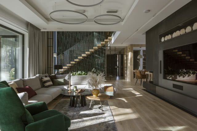 duży kominek, kanapa, fotel, stoliki kawowe, dywan, drewniana podłoga