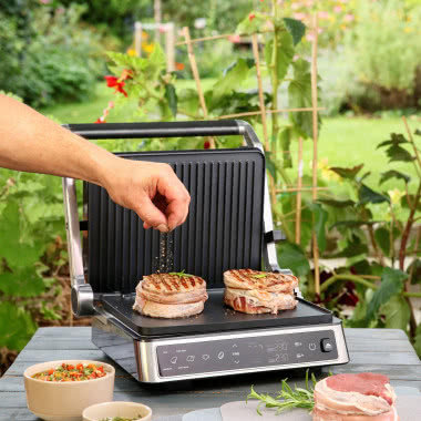 Cyfrowy grill kontaktowy PRESIDENT z ekranem dotykowym podczas grillowania steków w ogrodzie.