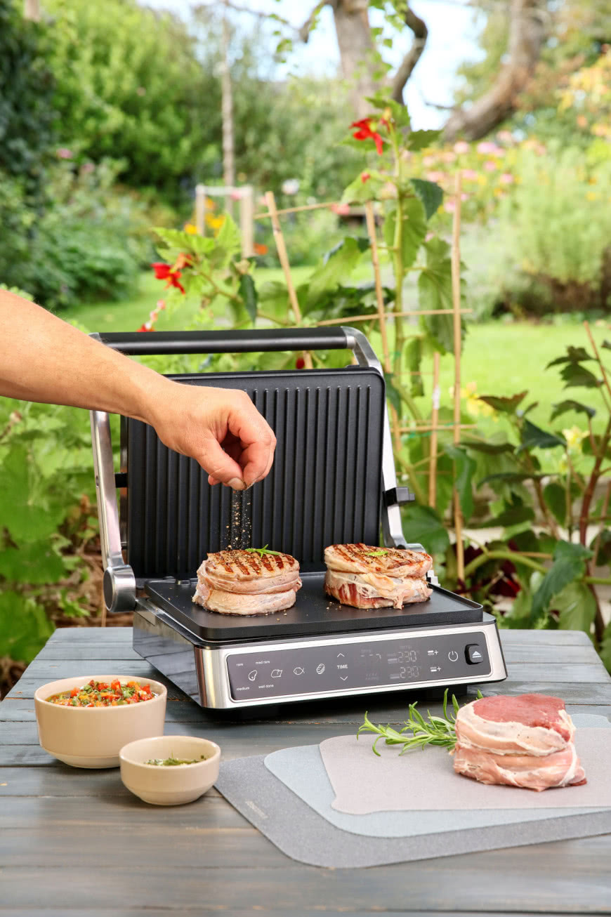 Cyfrowy grill kontaktowy PRESIDENT z ekranem dotykowym podczas grillowania steków w ogrodzie.