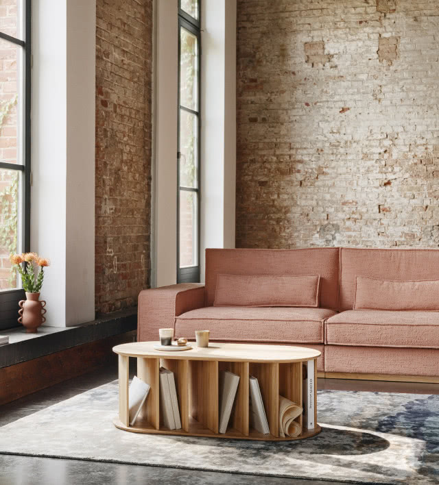 stolik PURRO z przegrodami na książki, kanapa, duże okna, cegła na ścianie, dywan