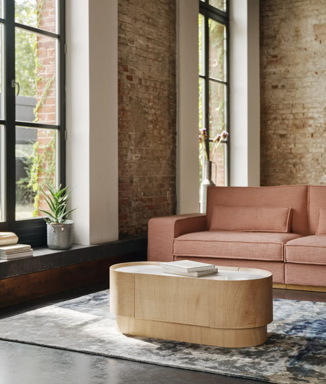 stolik TWIN, kanapa, duże okna, cegła na ścianie, dywan, kwiat w doniczce, książki na parapecie