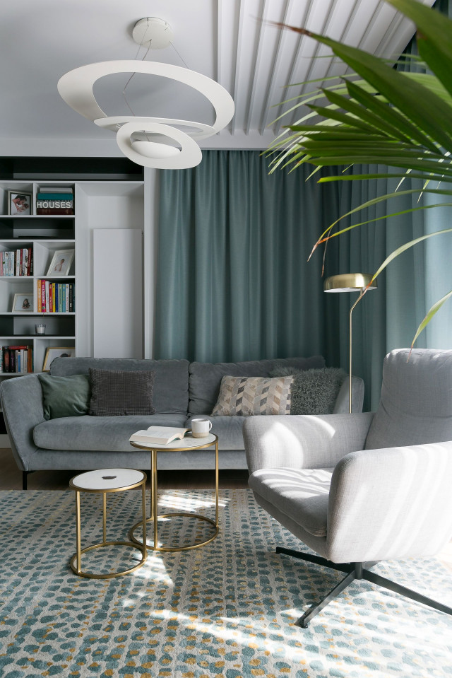 Szara sofa na tle miętowej zasłony w salonie