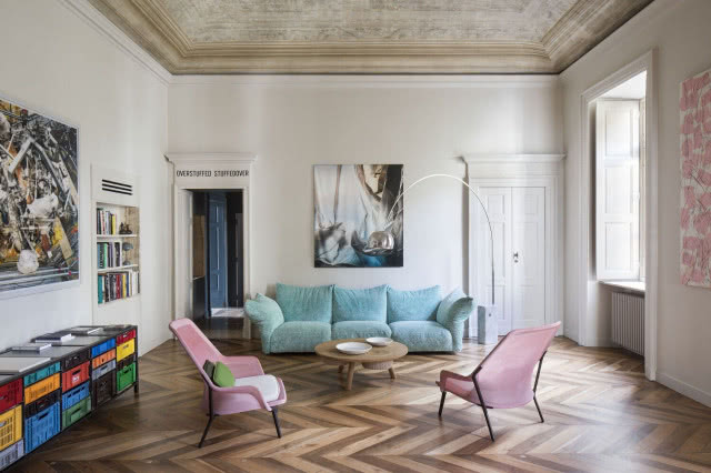 sofa pod obrazem z dwoma różowymi fotelami