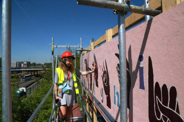 artystka na rusztowaniu maluje mural