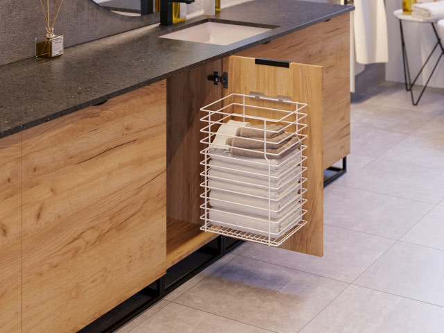 kosz na ręczniki, czarny blat łazienkowy, wpuszczana umywalka, lustro, patyczki zapachowe, drewniane fronty szafek łazienkowych