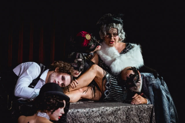 siedząca kobieta, przy niej klęczą mężczyźni