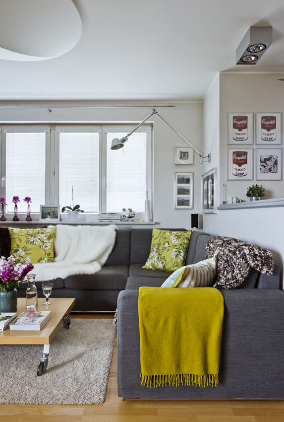 Ściany w salonie mają chłodny jasnoszary kolor,...