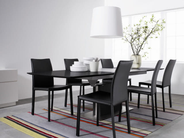 Stół Occa z dodatkowym blatem, wykończony fornirem dębowym barwionym na czarno oraz lakierem koloru stali matowej, wykonany z drewna i stali, krzesła Zarra pokryte czarną klejoną skórą, BOCOCNCEPT