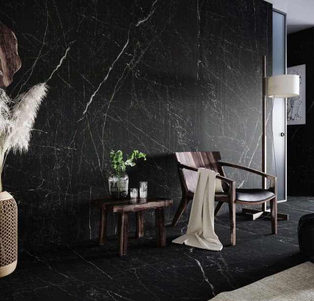 czarny naturalny kamień na ścianie, stolik kawowy, fotel, ręcznik, lampa podłogowa, wazon, obraz