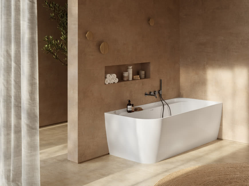 Biała wanna ANTIGUA marki RONAL Bathrooms w eleganckiej łazience w ciepłych, beżowych odcieniach z czarną armaturą.
