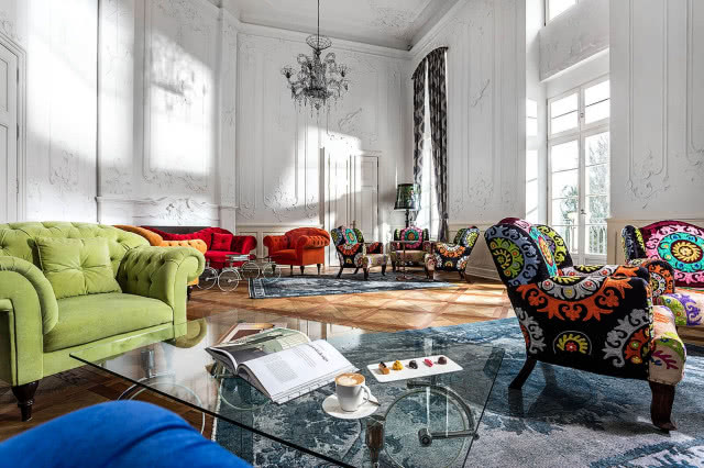 kolorowe lobby z fotelami , wysoki sufit ze sztukateriami i żyrandolem pałacowym