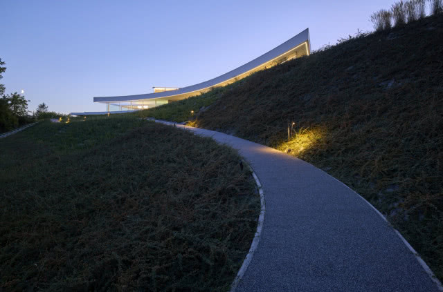 Dom schowany za fałdem ziemi. Widok z podjazdu.