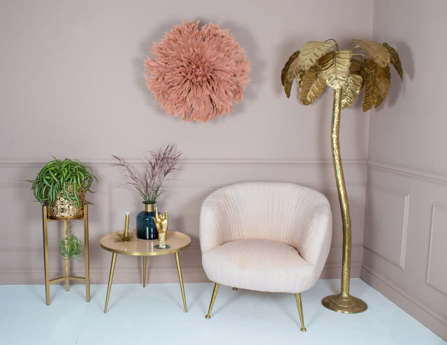 Zdjęcie przedstawiające meble i dekoracje w stylu boho na tle ściany w kolorze pudrowego różu