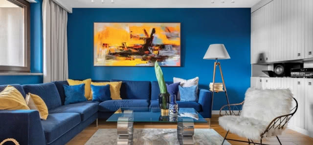 żółty obraz nad granatową kanapą