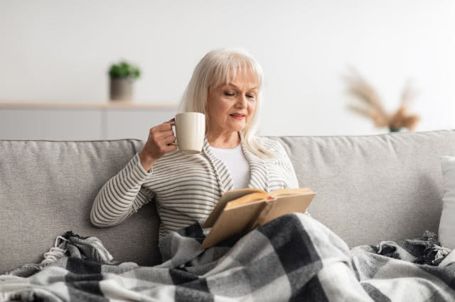 komoda, kanapa, Pani czytająca książkę, koc, kubek