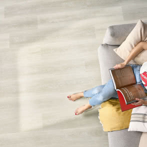 winylowe panele imitujące naturalne drewno, kanapa, poduszki ozdobne, książka, kobieta