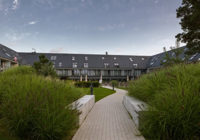 widok na niski hotel z piaszczystej ścieżki