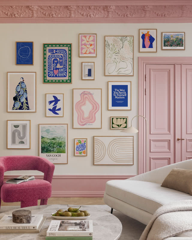 obrazy rozwieszone nieregularnie na różowej ścianie