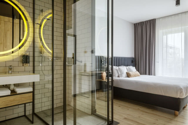 sypialnia z przeszkloną łazienka i podświetlanym lustrem