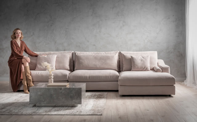 duży narożnik, stolik kawowy, dywan, drewniany wazon z ususzoną trawą