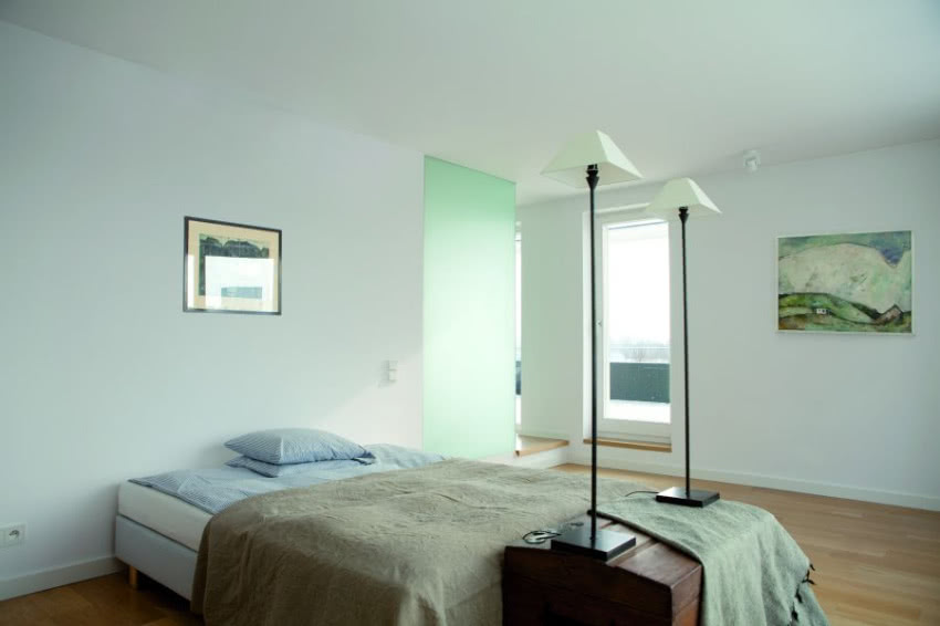 Chłód minimalistycznej sypialni ocieplają obrazy...