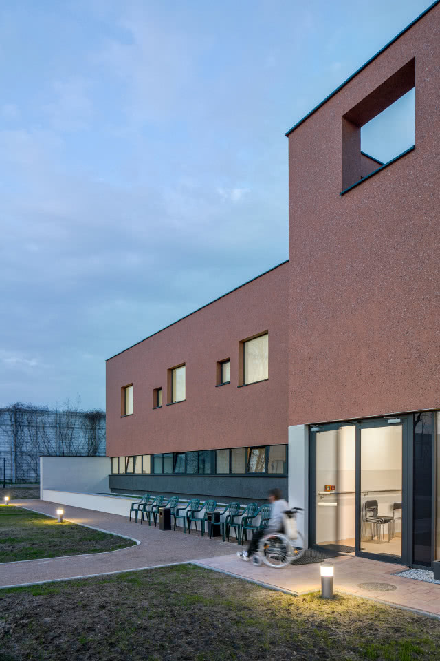 budynek ujęty z boku z osobą niepełnosprawną na wózku