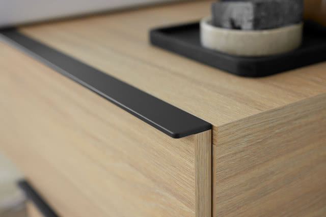  Zbliżenie na szafkę łazienkową w kolorze drewna z czarnym uchwytem