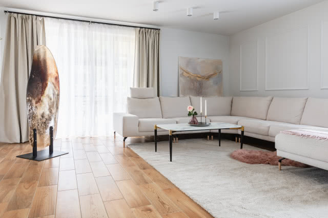 Jasny salon ze sztukaterią i obrazami na ścianach