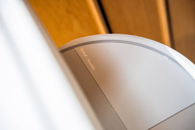 Robot sprzątający iRobot Roomba podczas pracy w nowoczesnym wnętrzu, częściowo schowany pod meblem.
