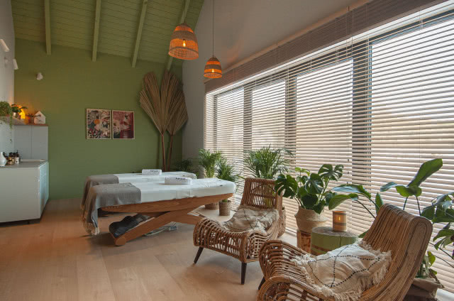 rattanowe fotele, łóżka, obrazy, kwiaty, drewniana podłoga, zielone ściany, umywalka, białe meble, świece, ręczniki