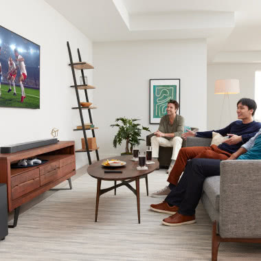 JBL Bar 800 , telewizor, półki w kształcie drabiny, komoda, stolik kawowy, kanapa, obraz, lampa podłogowa