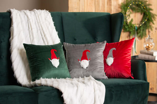 ozdobne poduszki ze skrzatami, kanapa w kolorze butelkowej zieleni, koc, stolik kawowy,