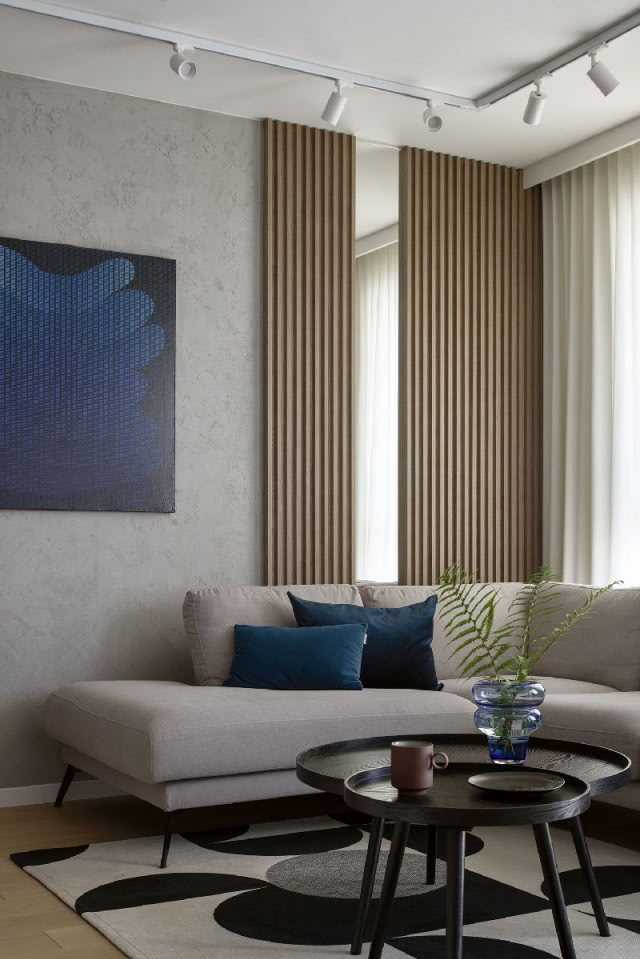 Salon z betonem i drewnianymi lamelami na ścianie z kobaltowymi dodatkami