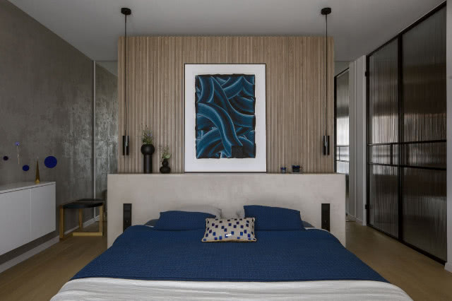 Sypialnia z drewnem i mikrocementem i niebieskimi dodatkami