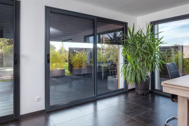 rolety przeciwsłoneczne zewnętrzne, taras, stół z krzesłami, duże okno tarasowe, duża dracena, 