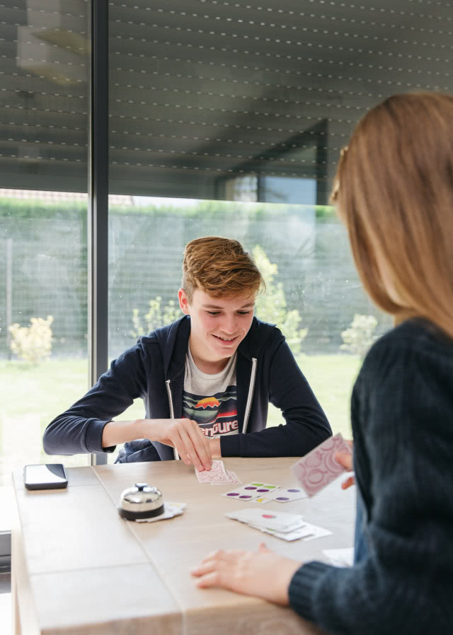 dzieci grające w karty, rolety zewnętrzne, duże okno