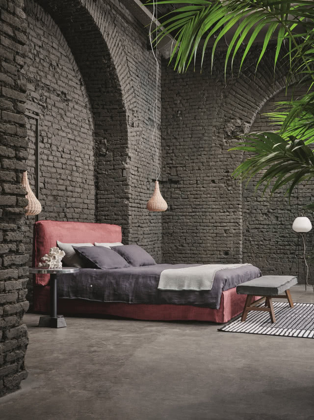 łóżko kontynentalne na tle ściany z cegłą