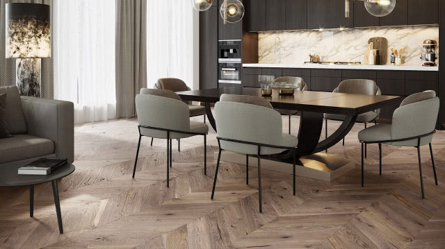 drewniana podłoga ułożona w jodełkę, duży stół z krzesłami, kominek, komoda, szare meble kuchenne, fotele, zegar ścienny