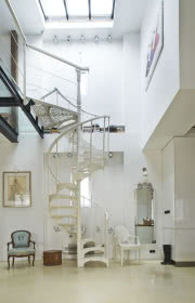 Kręte ażurowe schody w kolorze białym są ozdobą wnętrza