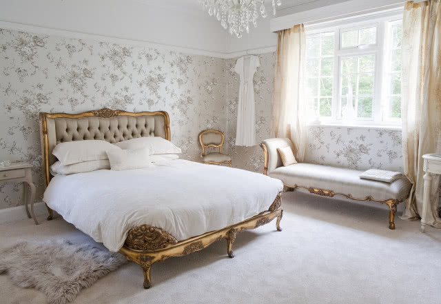 Zdjęcie jasnej sypialni z pikowanym łóżkiem w złotej ramie