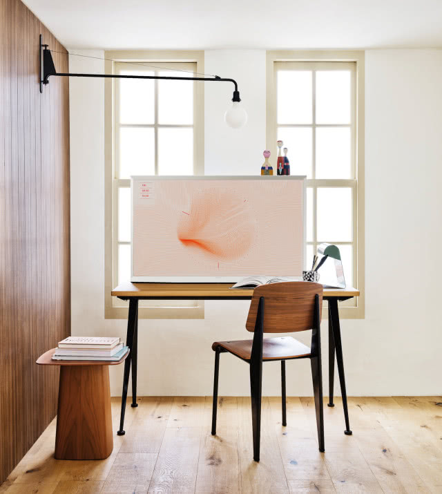 telewizor na biurku przedstawiający sztukę, krzesło, drewniany stolik drewniana podłoga, lampa ścienna, lampa biurkowa