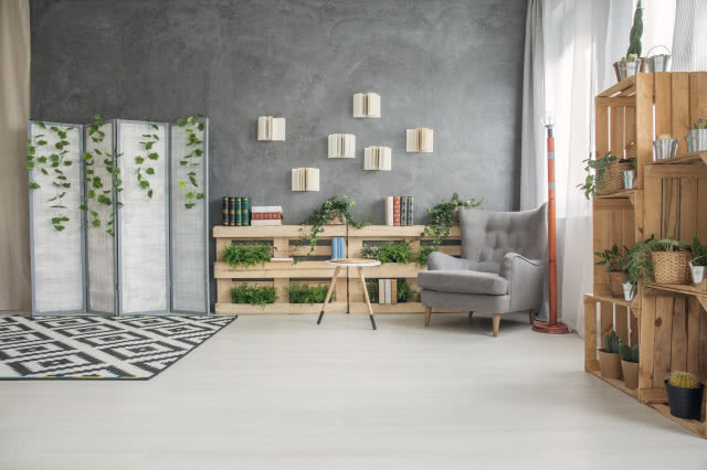 półki zrobione z palet oraz z drewnianych skrzynek, szara ściana, szary fotel