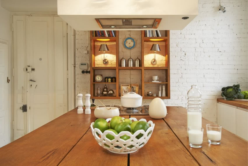 Drewniany blat i półki ocieplają białą kuchnię.