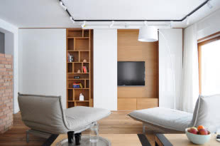 Biały przesuwany panel może zakryć telewizor, odsłaniając półki na książki