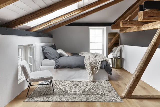 poddasze, belki drewniane, sypialnia, duże łóżko, szara pościel, białe krzesło, drewniana podłoga, dywan