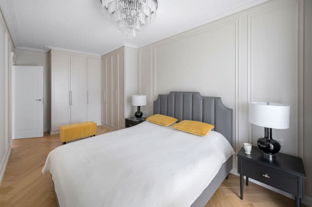 Dodatki w kolorze musztardowym, wybrane przez panią domu, ożywiają wnętrze. Funkcjonalny puf przy  szafach to wygodne rozwiązanie.