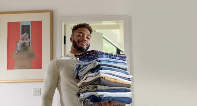 Pan niesie wyprasowane i złożone ubrania, obraz na ścianie